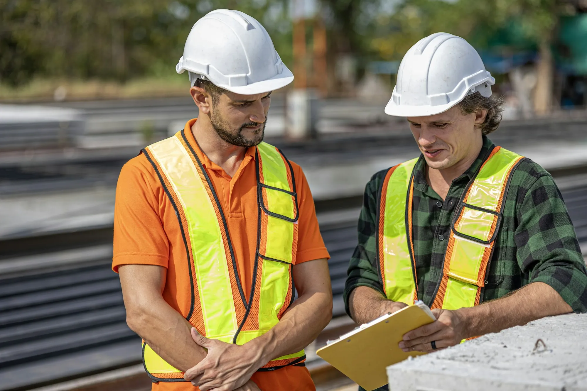 Two electricians in safety vests and hard hats talking on a job site