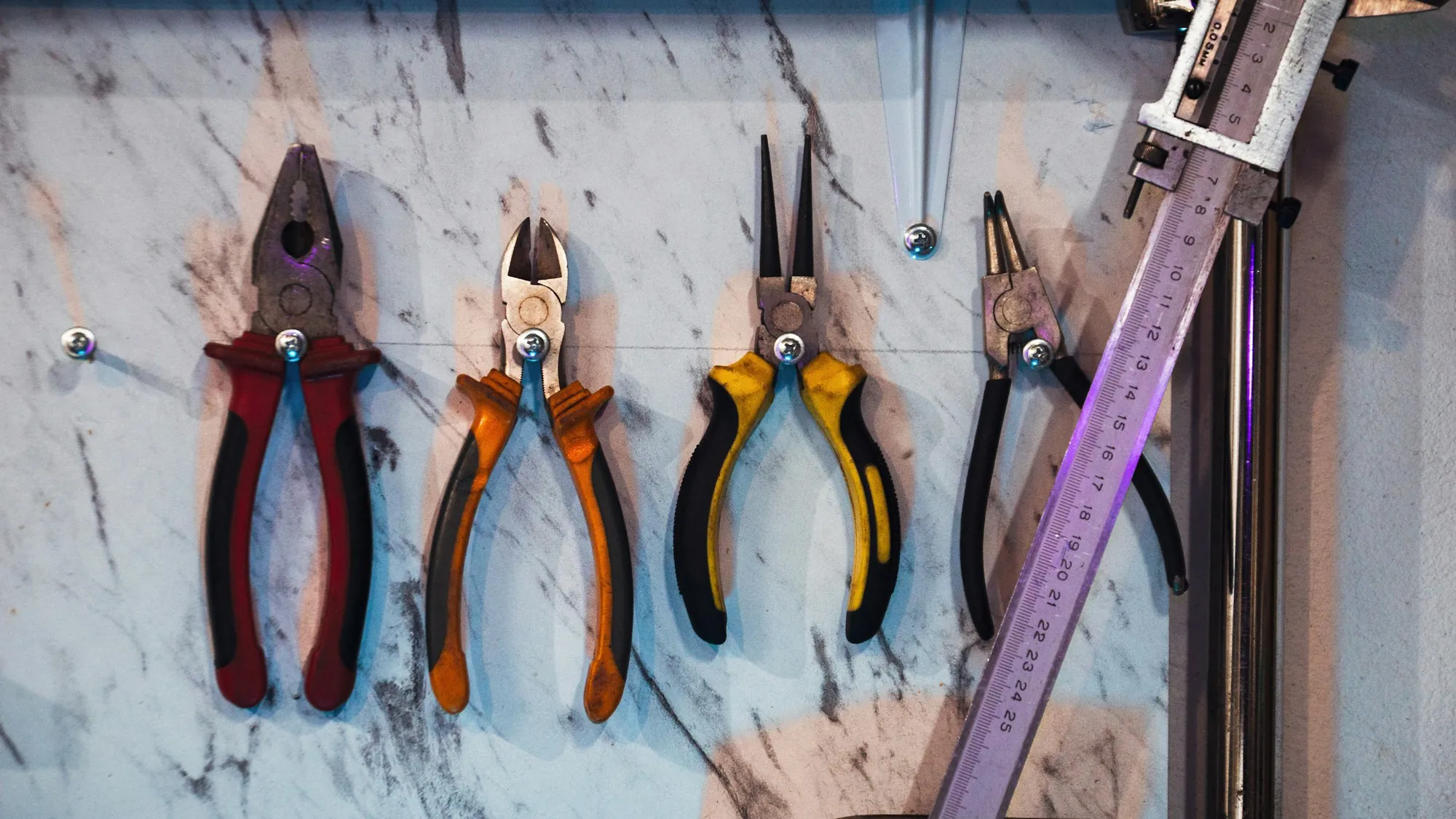 Pliers and cutters hanging in a row on a workshop wall