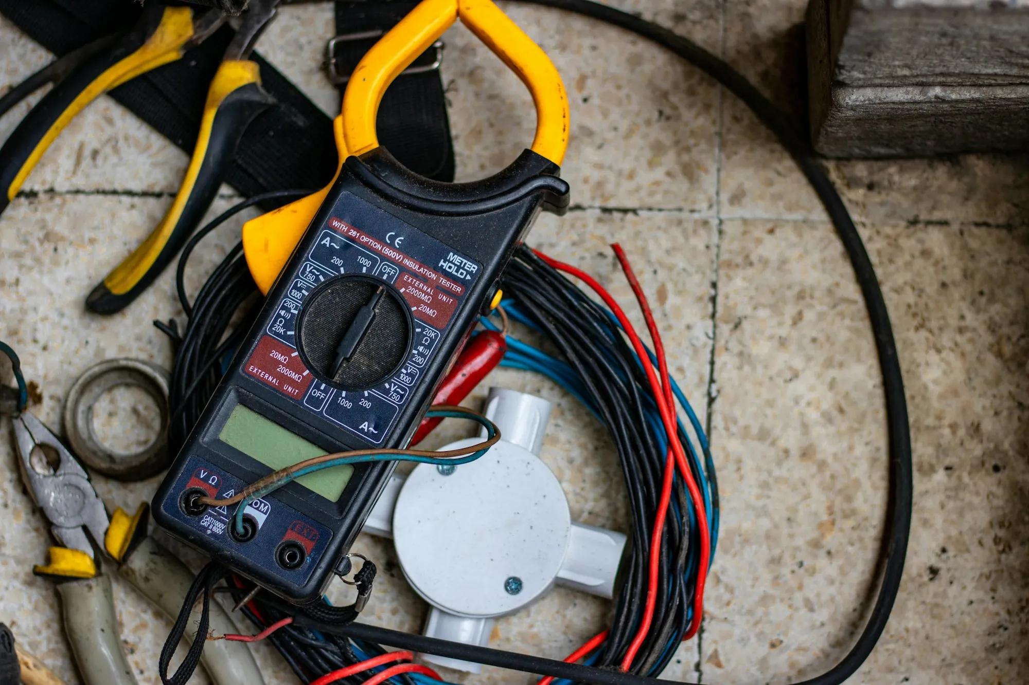 Multimeter with test leads beside a coil of wire