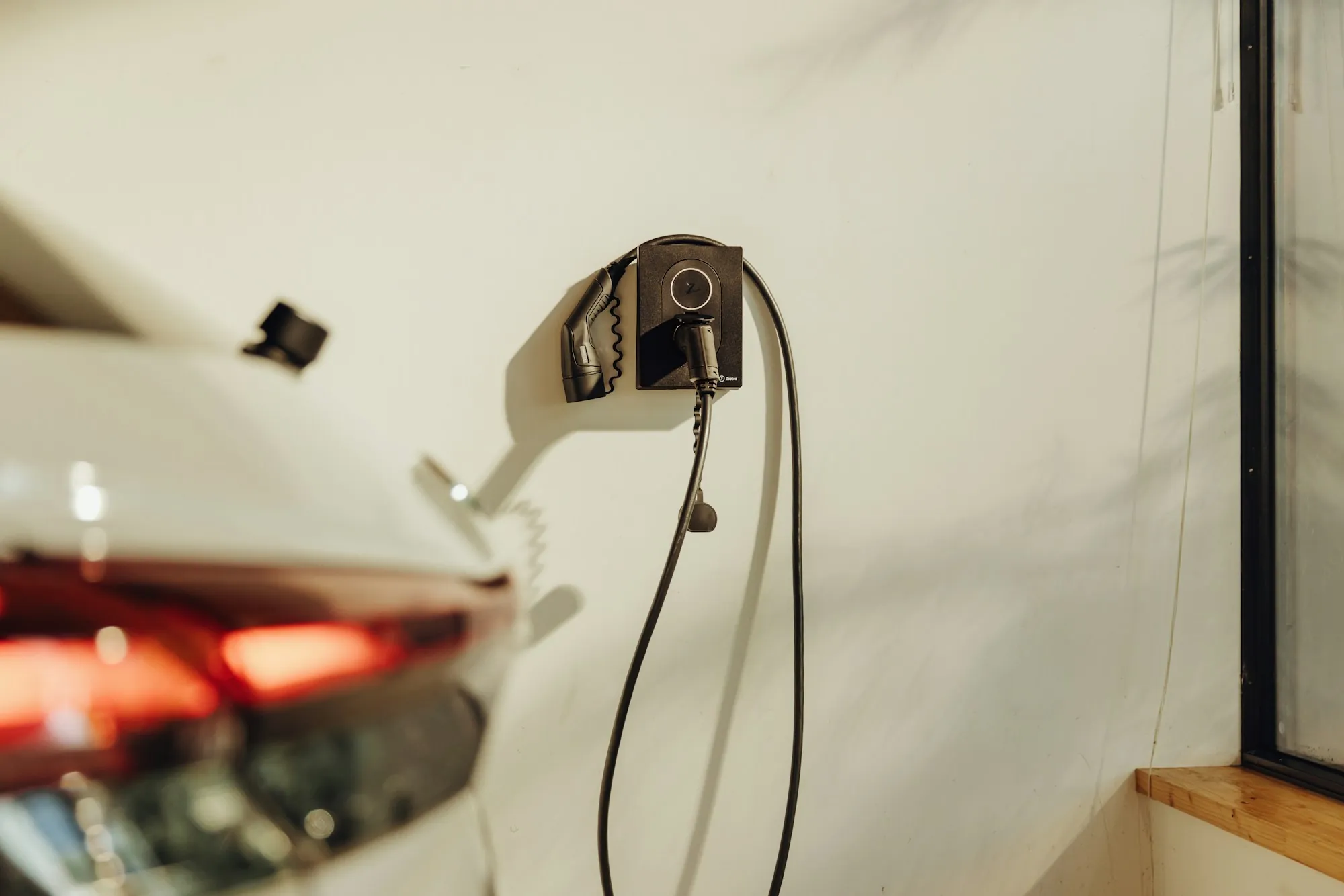 Charging cable plugged into a white electric car in a garage