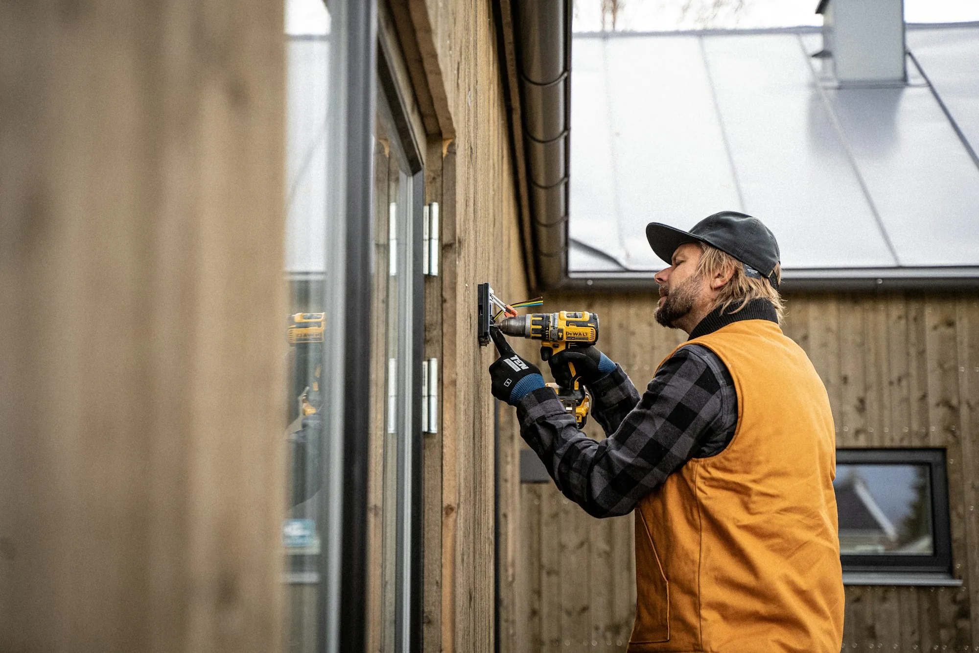 Electrician drilling into the exterior wall of a home to run new wiring