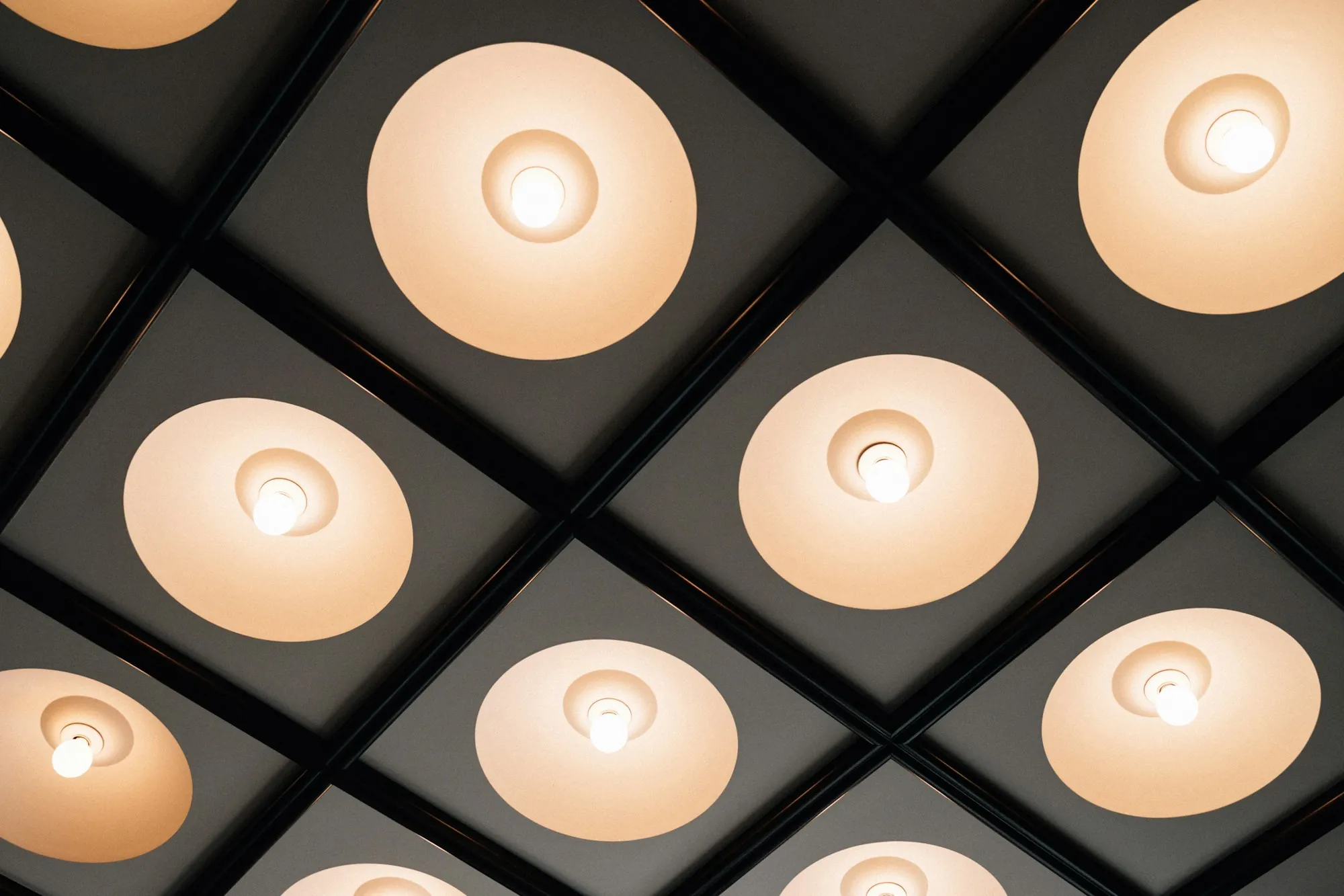 Grid of round recessed ceiling lights glowing warm white
