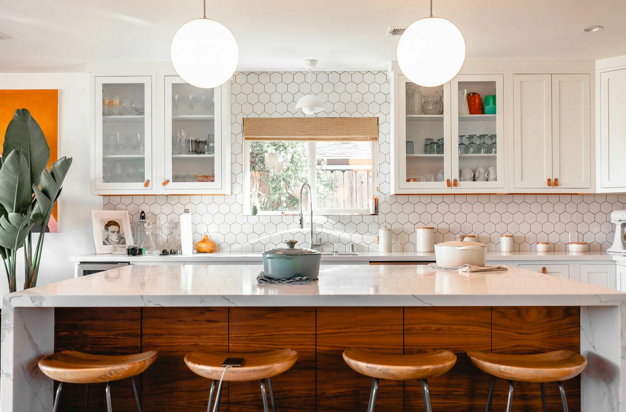 Bright kitchen with white cabinets, pendant lights and stools at the counter