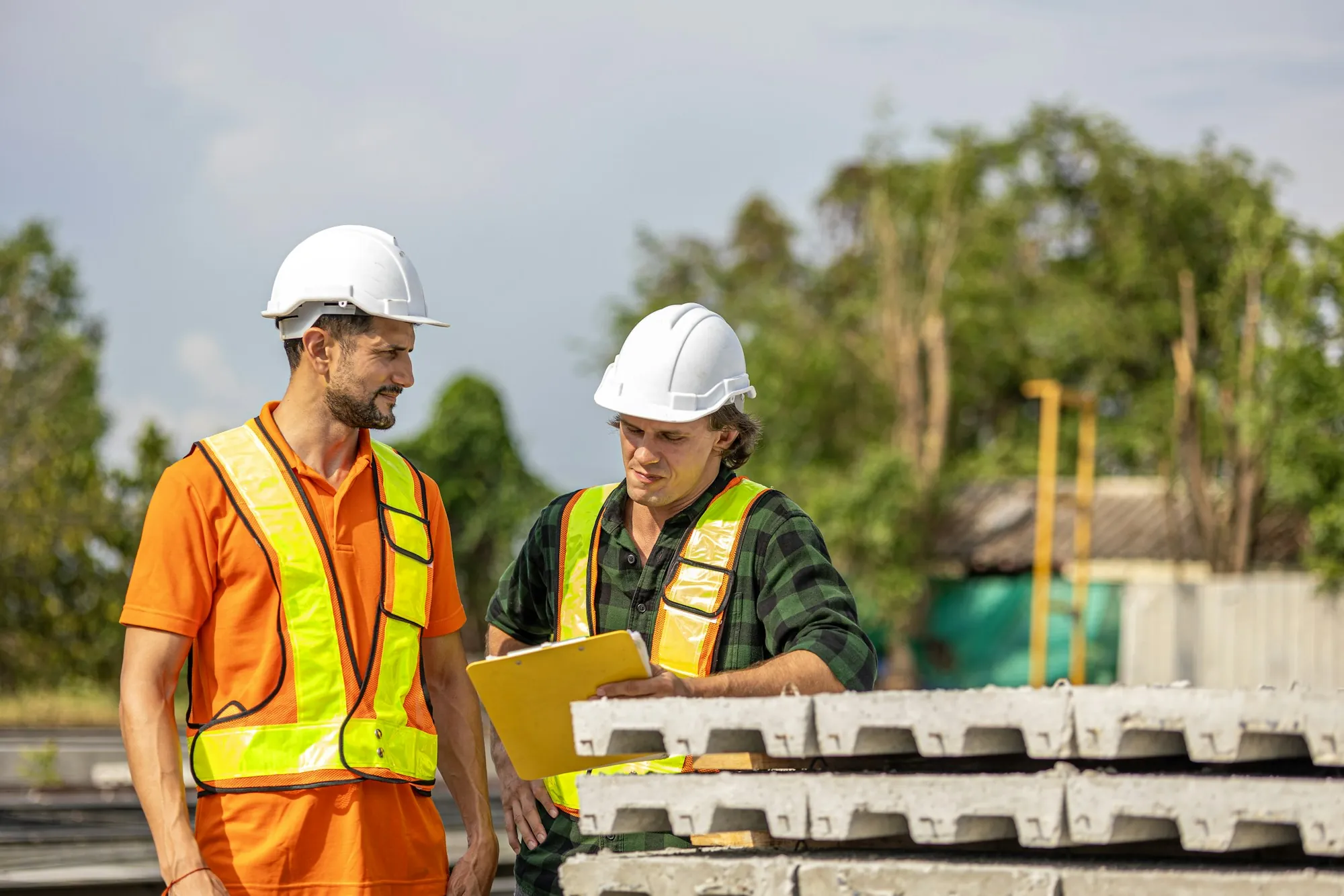 Two electricians in hard hats going over a job plan outdoors
