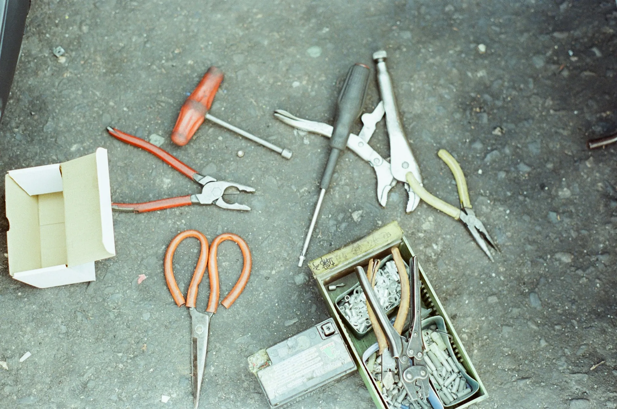 Hand tools and wire connectors spread on a concrete floor